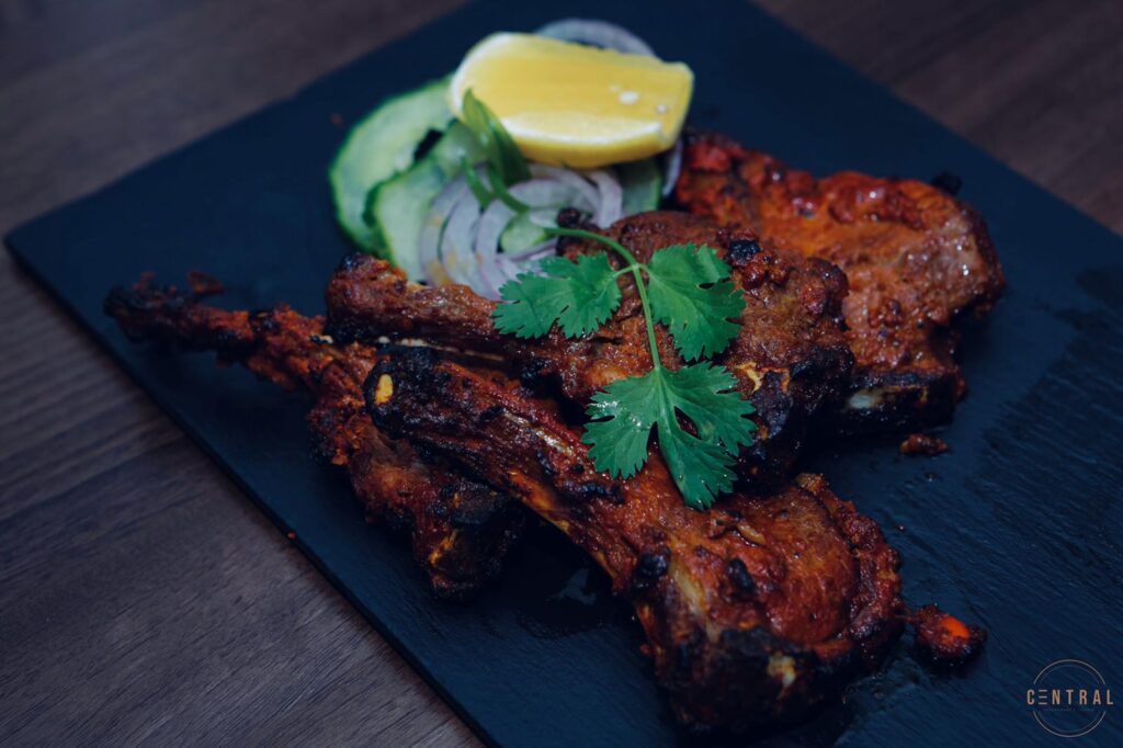 Sticky lamb chops on a slate with lemon and coriander