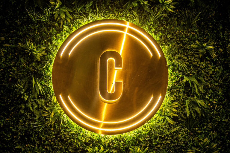 The illuminated Central logo on a green wall